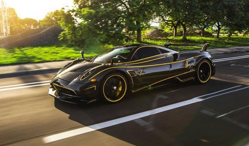 A rolling shot of a black Huayra BC with yellow accent lines along the curves of its body.