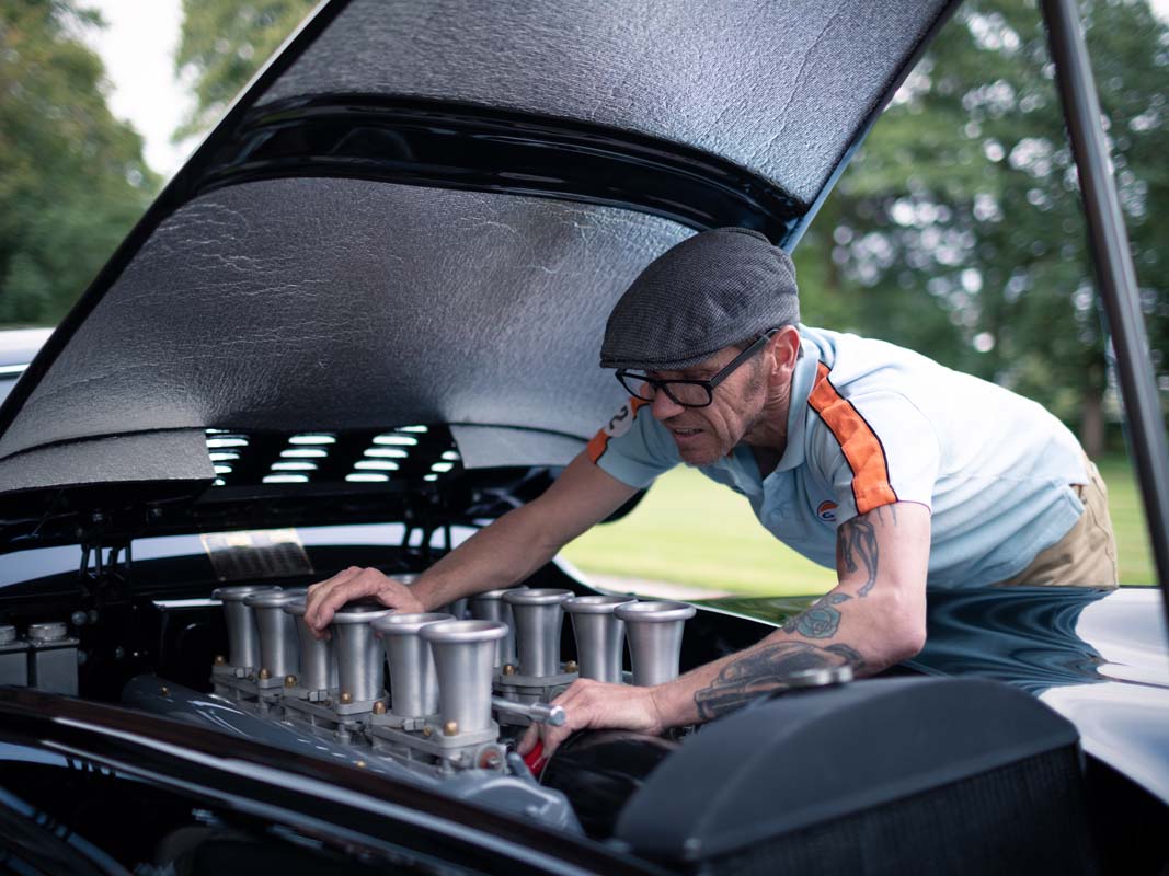 Builder Justin Hills is shown under the Jag's elegant bonnet making adjustments to its engine.
