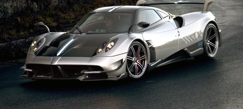 Front three quarter view of a Huayra BC going through a right-handed corner on a mountain road.|Rear view of the Huayra BC showing its big rear wing